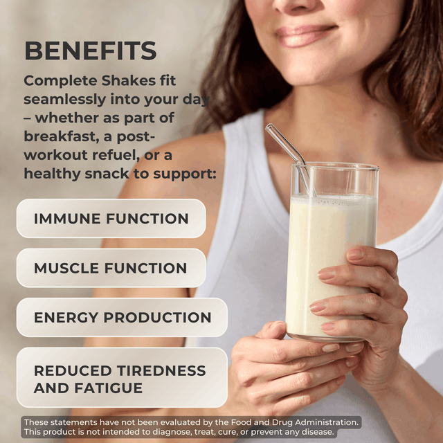 A woman holds a glass of creamy shake while text on the left lists benefits: immune function, muscle function, energy production, and reduced tiredness and fatigue. The image is promotional and not a clean standalone product shot.